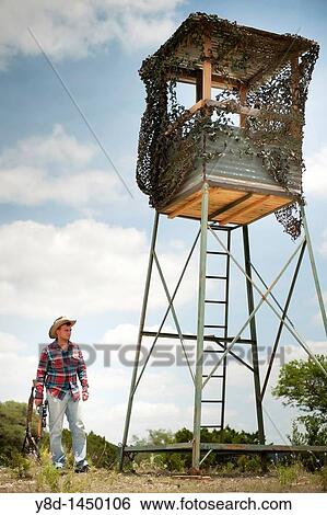 Hunting season in America - Man with cowboy hat and hunting rifle standing next to deer blind View Large Photo Image Stock Photograph - Hunting season in America - Man with cowboy hat and hunting rifle standing next to deer blind. Fotosearch