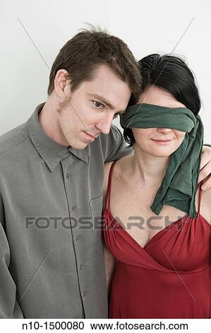 Stock Image - Husband and his blindfolded wife. Fotosearch