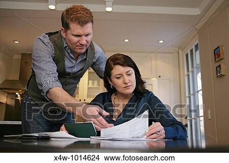 Husband is angry as married couple pays their bills and reviews their finances together View Large Photo Image Picture - Husband is angry as married couple pays their bills and reviews their finances together. Fotosearch