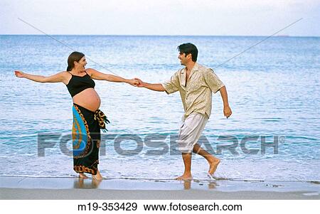 Stock Photo - husband with his pregnant wife on the beach. Fotosearch