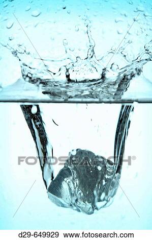 ICE CUBE SPLASHING INTO WATER. View Large Photo Image Stock Photo - ICE CUBE SPLASHING INTO WATER.. Fotosearch