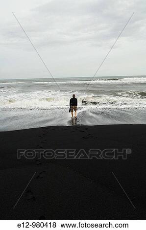 Iceland, Vik village, church, man with feet in the sea at the black sand beach. View Large Photo Image Stock Photo - Iceland, Vik village, church, man with feet in the sea at the black sand beach.. Fotosearch