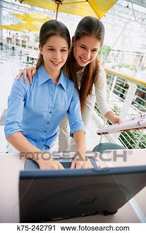 Stock Image - identical twins using a laptop. Fotosearch
