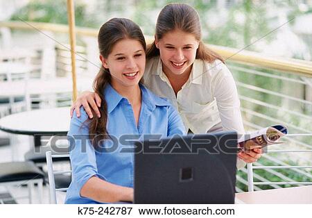 Stock Photo - Identical twins using a laptop. Fotosearch