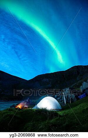 Stock Photo - Illuminated tent with Northern Lights in sky at Kvalvika beach, Moskenesoy, Lofoten Islands, Norway.. Fotosearch