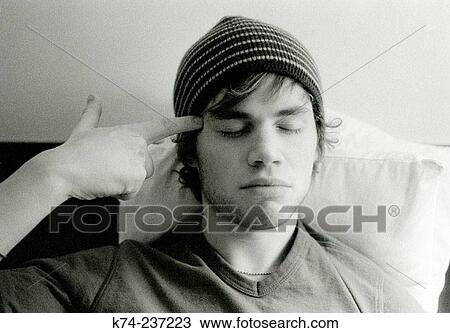 image of young man wearing hat and finger pointing at head View Large Photo Image Stock Image - image of young man wearing hat and finger pointing at head. Fotosearch