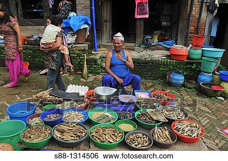 Stock Photograph - In the morning market the man selling dry fishes. Bhaktapur, Kathmandu Valley, Nepal. Fotosearch
