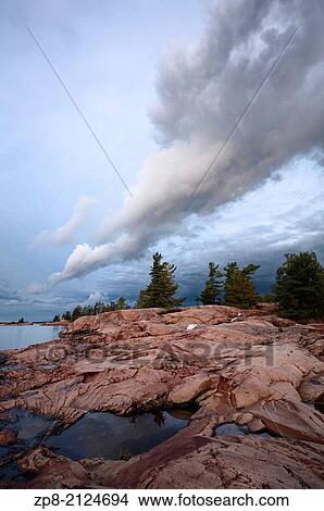Incredible cloud formations hanging over Pink Granite along the shores of Georgian Bay in Killarney Provincial Park, Ontario, Canada. View Large Photo Image Picture - Incredible cloud formations hanging over Pink Granite along the shores of Georgian Bay in Killarney Provincial Park, Ontario, Canada.. Fotosearch