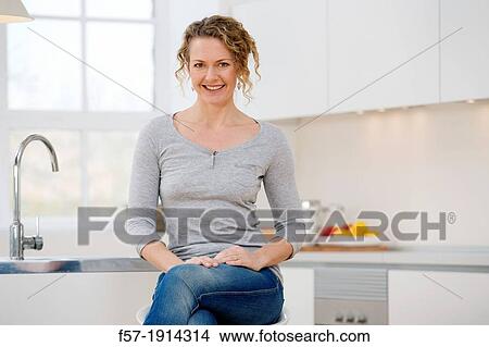 Independent young woman sitting her kitchen View Large Photo Image Picture - Independent young woman sitting her kitchen. Fotosearch