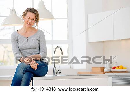 Independent young woman sitting her kitchen View Large Photo Image Stock Photo - Independent young woman sitting her kitchen. Fotosearch
