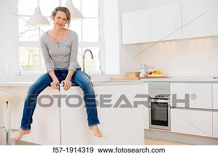 Independent young woman sitting her kitchen View Large Photo Image Stock Photo - Independent young woman sitting her kitchen. Fotosearch