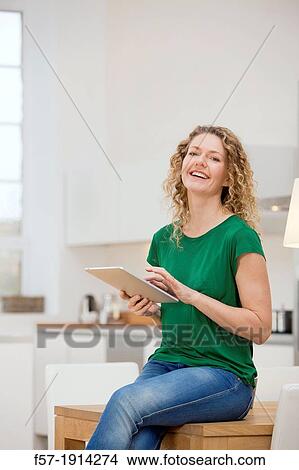 Independent young woman working at home on a tablet computer View Large Photo Image Picture - Independent young woman working at home on a tablet computer. Fotosearch