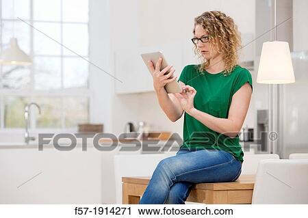 Stock Image - Independent young woman working at home on a tablet computer. Fotosearch