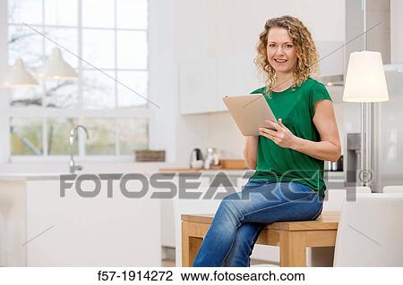 Independent young woman working at home on a tablet computer View Large Photo Image Stock Image - Independent young woman working at home on a tablet computer. Fotosearch