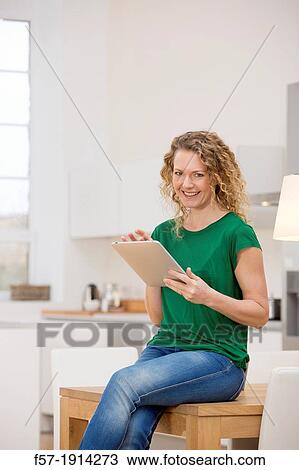 Independent young woman working at home on a tablet computer View Large Photo Image Stock Image - Independent young woman working at home on a tablet computer. Fotosearch