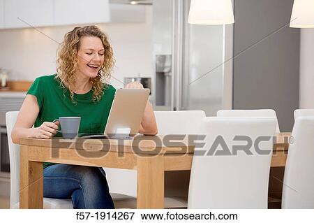 Independent young woman working at home on a tablet computer View Large Photo Image Stock Photo - Independent young woman working at home on a tablet computer. Fotosearch