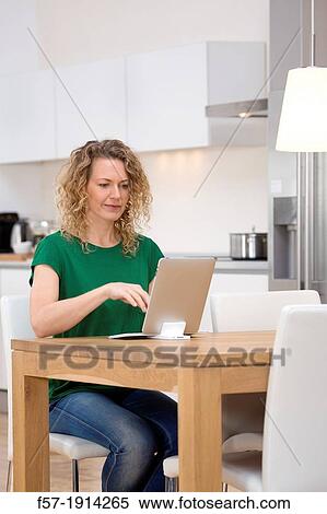 Independent young woman working at home on a tablet computer View Large Photo Image Stock Photography - Independent young woman working at home on a tablet computer. Fotosearch