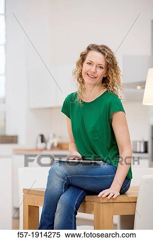 Independent young woman working at home on a tablet computer View Large Photo Image Stock Photography - Independent young woman working at home on a tablet computer. Fotosearch