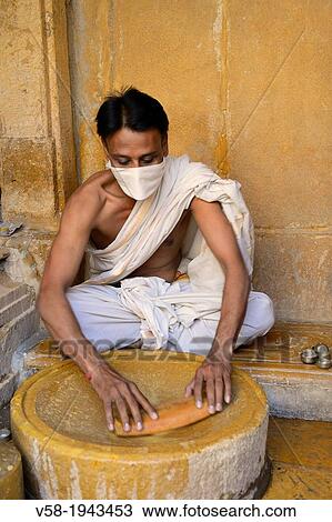 Stock Image - India, Rajasthan, Jaisalmer, Parshvanath temple, Jain devotee preparing sandalwood paste for the worship of the Tirthankaras or ford makers.. Fotosearch