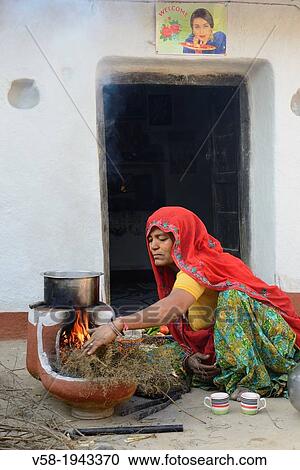 Stock Image - India, Rajasthan, Tonk region, Damun village, Meena woman making morning tea.. Fotosearch