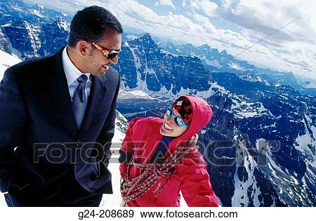 Stock Photo - Indian businessman conversing with climber on high mountain summit. Banff National Park. Canada. Fotosearch