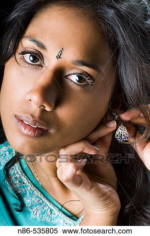 Indian girl putting on jewelry View Large Photo Image Stock Photography - Indian girl putting on jewelry. Fotosearch