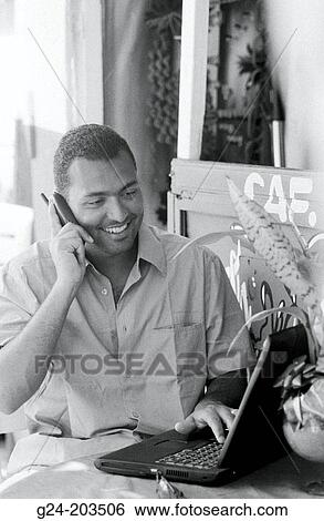 Indian man on cell phone, working with laptop View Large Photo Image Stock Photograph - Indian man on cell phone, working with laptop. Fotosearch