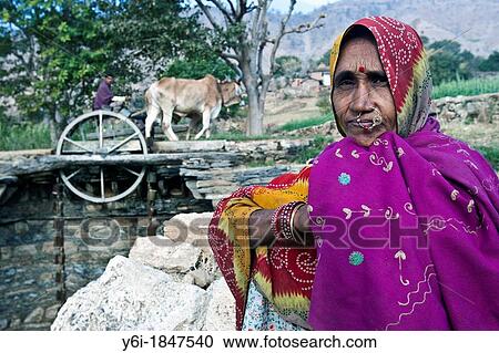 Stock Image - Indian woman in traditional clothes at water wheel well Rajasthan India. Fotosearch