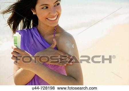 Stock Photo - Indian woman on the beach with sun cream. Fotosearch