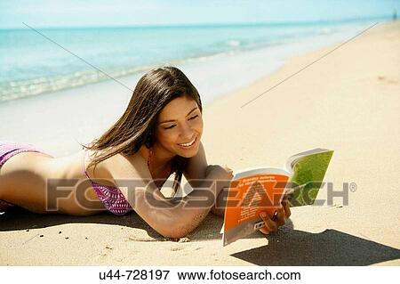 Stock Photo - Indian woman reading a book on the beach. Fotosearch