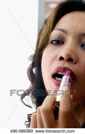 Indonesian woman applying lipstick - close-up View Large Photo Image Stock Photo - Indonesian woman applying lipstick - close-up. Fotosearch