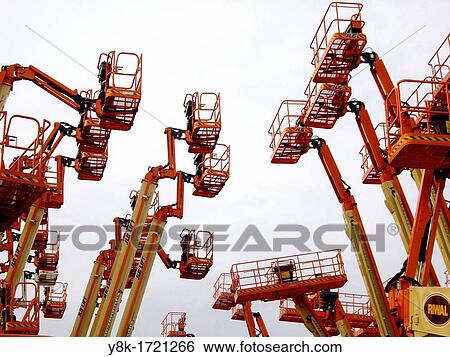 Stock Photograph - Industrial aerial work platforms facing eachother like getting into a clash against white background in Dordrecht, Zuid Holland, The Netherlands. Fotosearch