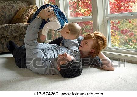 Infant boy being lifted by his father while his mother looks on. View Large Photo Image Stock Image - Infant boy being lifted by his father while his mother looks on.. Fotosearch