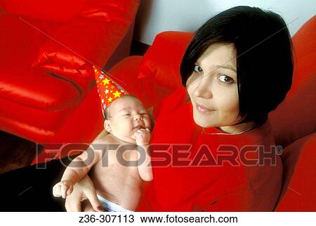 Stock Image - Infant boy in New Year hat with mother. Fotosearch