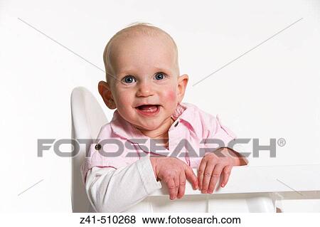 Stock Photo - Infant boy sitting on a high chair smiling. Fotosearch