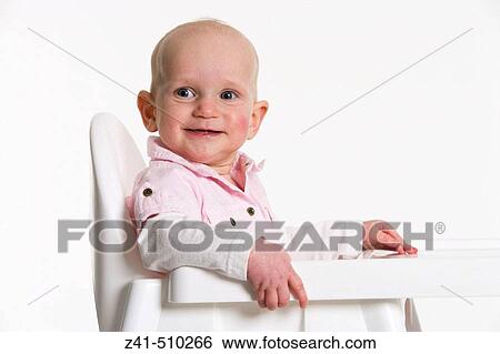 Infant boy sitting on a high chair smiling View Large Photo Image Stock Photograph - Infant boy sitting on a high chair smiling. Fotosearch