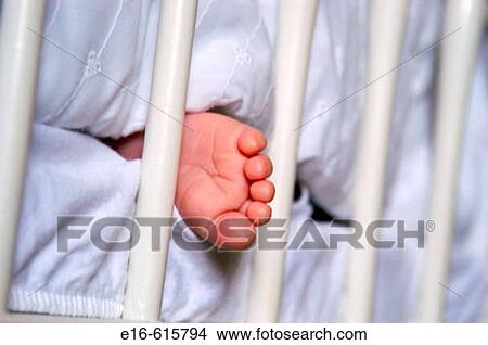Picture - infant foot sticking out of crib. Fotosearch