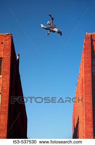Inline skater jumps between two buildings. View Large Photo Image Stock Image - Inline skater jumps between two buildings.. Fotosearch