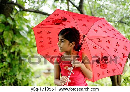 Innocent young girl holding an umbrella and enjoying the monsoon rains View Large Photo Image Stock Image - Innocent young girl holding an umbrella and enjoying the monsoon rains. Fotosearch
