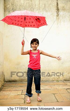 Innocent young girl smiling in the rain while holding an umbrella View Large Photo Image Picture - Innocent young girl smiling in the rain while holding an umbrella. Fotosearch