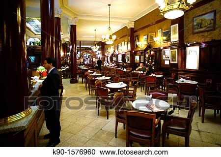 Stock Image - Inside Cafe Tortoni with a waiter standing at the bar, chairs, tables and light, Buenos Aires, Argentina, South America. Fotosearch