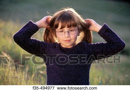 Intelligent girl with glasses fixing her hair View Large Photo Image Stock Photo - Intelligent girl with glasses fixing her hair. Fotosearch