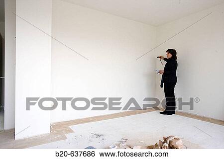 Interior decorator taking measures in empty room View Large Photo Image Stock Photograph - Interior decorator taking measures in empty room. Fotosearch