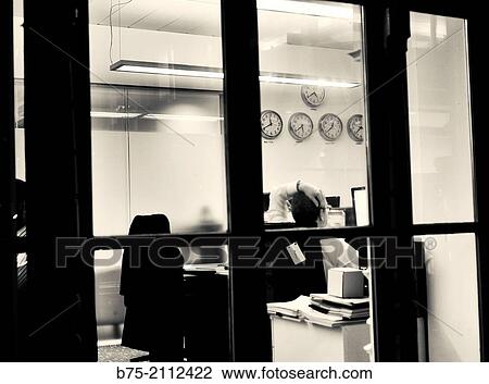 Interior of an office with a man sitting and relaxing in front of a computer and multiple clocks with different time on a wall. London, England, UK, Europe. View Large Photo Image Stock Image - Interior of an office with a man sitting and relaxing in front of a computer and multiple clocks with different time on a wall. London, England, UK, Europe.. Fotosearch