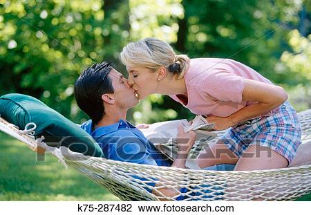 Interrupting his reading with a kiss View Large Photo Image Stock Image - Interrupting his reading with a kiss. Fotosearch
