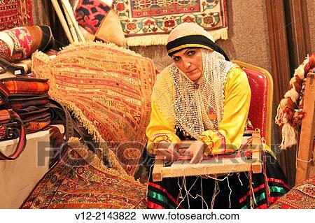 Stock Image - Iranian woman weaving a carpet. Fotosearch
