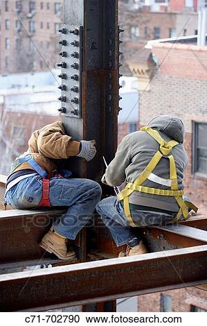 Iron/construction workers sitting on steel beam adjusting anchor bolts View Large Photo Image Stock Image - Iron/construction workers sitting on steel beam adjusting anchor bolts. Fotosearch
