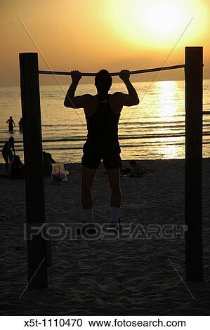 Israel, Tel Aviv, Physical work-out at sunset a man doing chin ups on the beach at sun set View Large Photo Image Stock Image - Israel, Tel Aviv, Physical work-out at sunset a man doing chin ups on the beach at sun set. Fotosearch