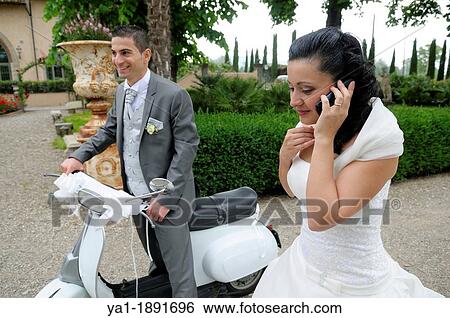 Stock Photograph - Italian wedding couple with a motor scooter Vespa in a garden park, Firenze, Tuscany, Italy. Fotosearch
