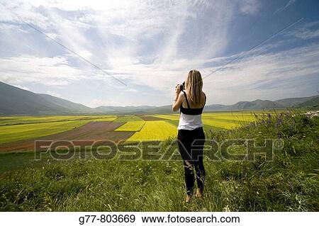Italy, Umbria, Norcia, Highland of Castelluccio di Norcia. Woman taking pictures of Lentils Fields View Large Photo Image Stock Photo - Italy, Umbria, Norcia, Highland of Castelluccio di Norcia. Woman taking pictures of Lentils Fields. Fotosearch